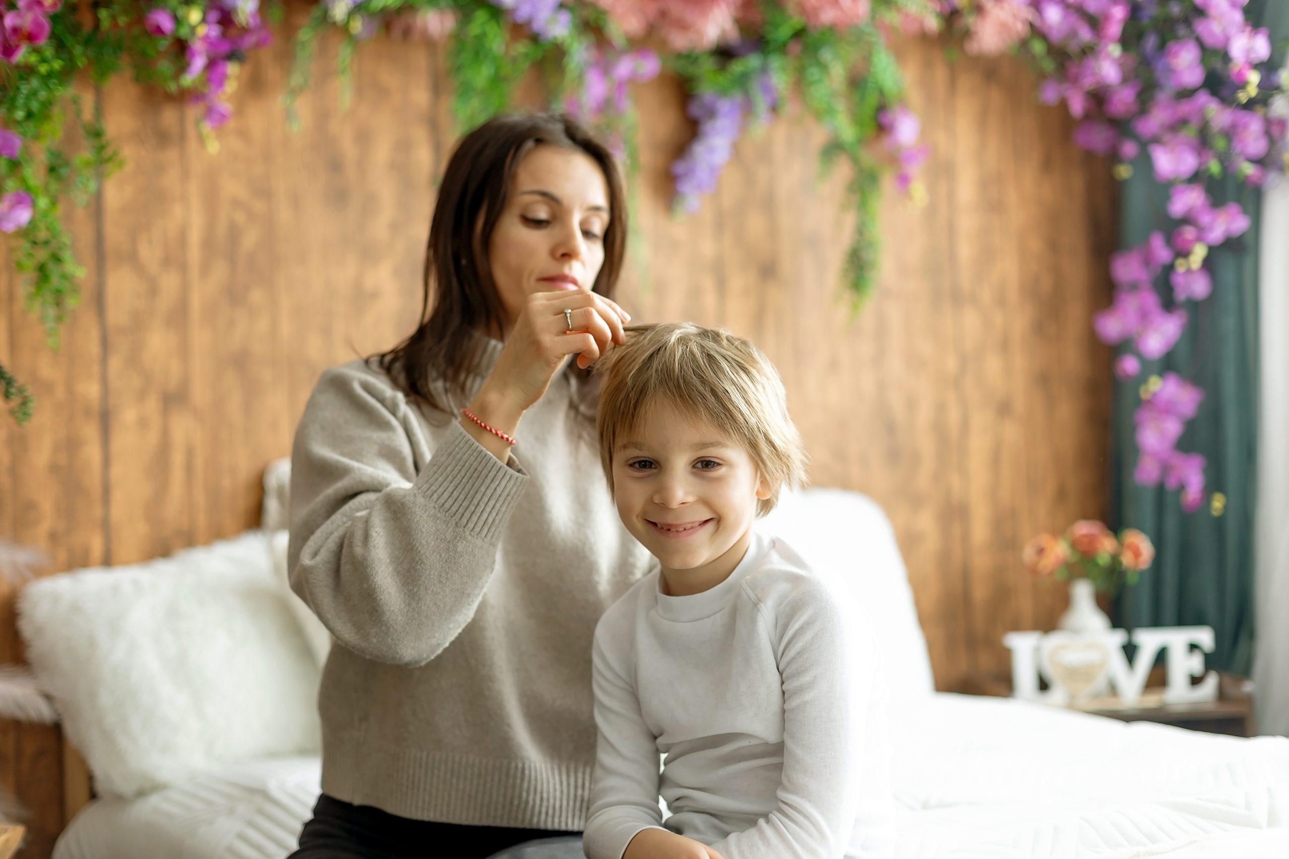 Mother carefully checking her son's hair for head lice at home