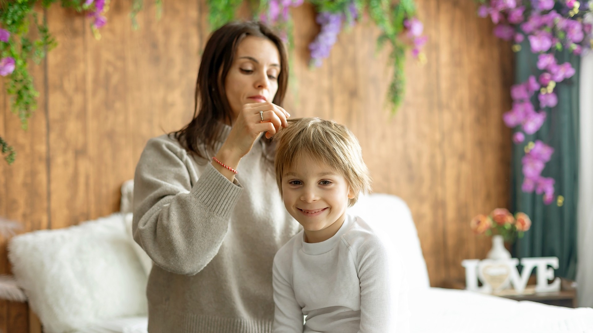 Parent gently parting their child's hair near the part line to check the scalp for lice during a post-treatment recheck.