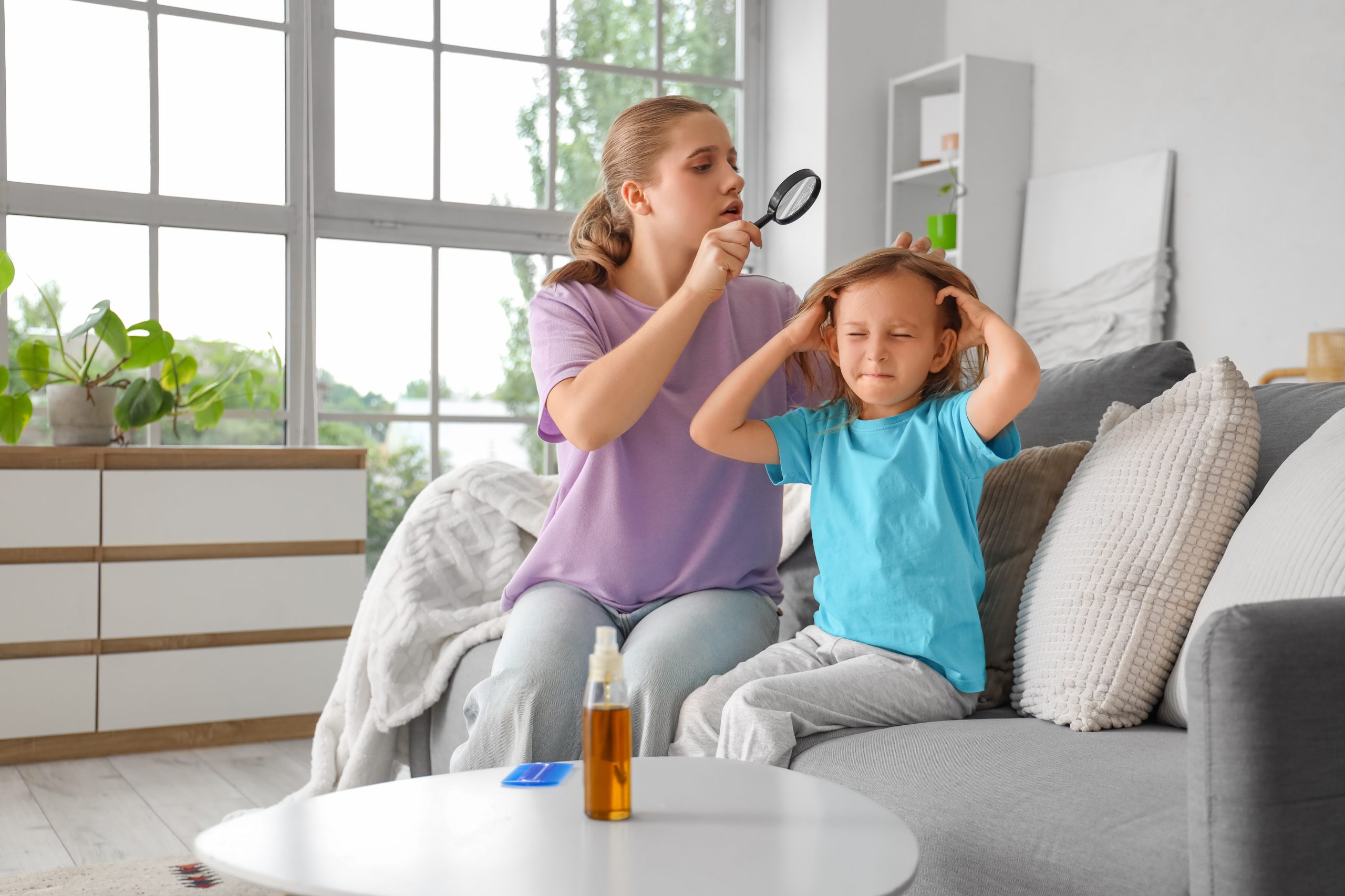 Mother using magnifier to check child head for lice