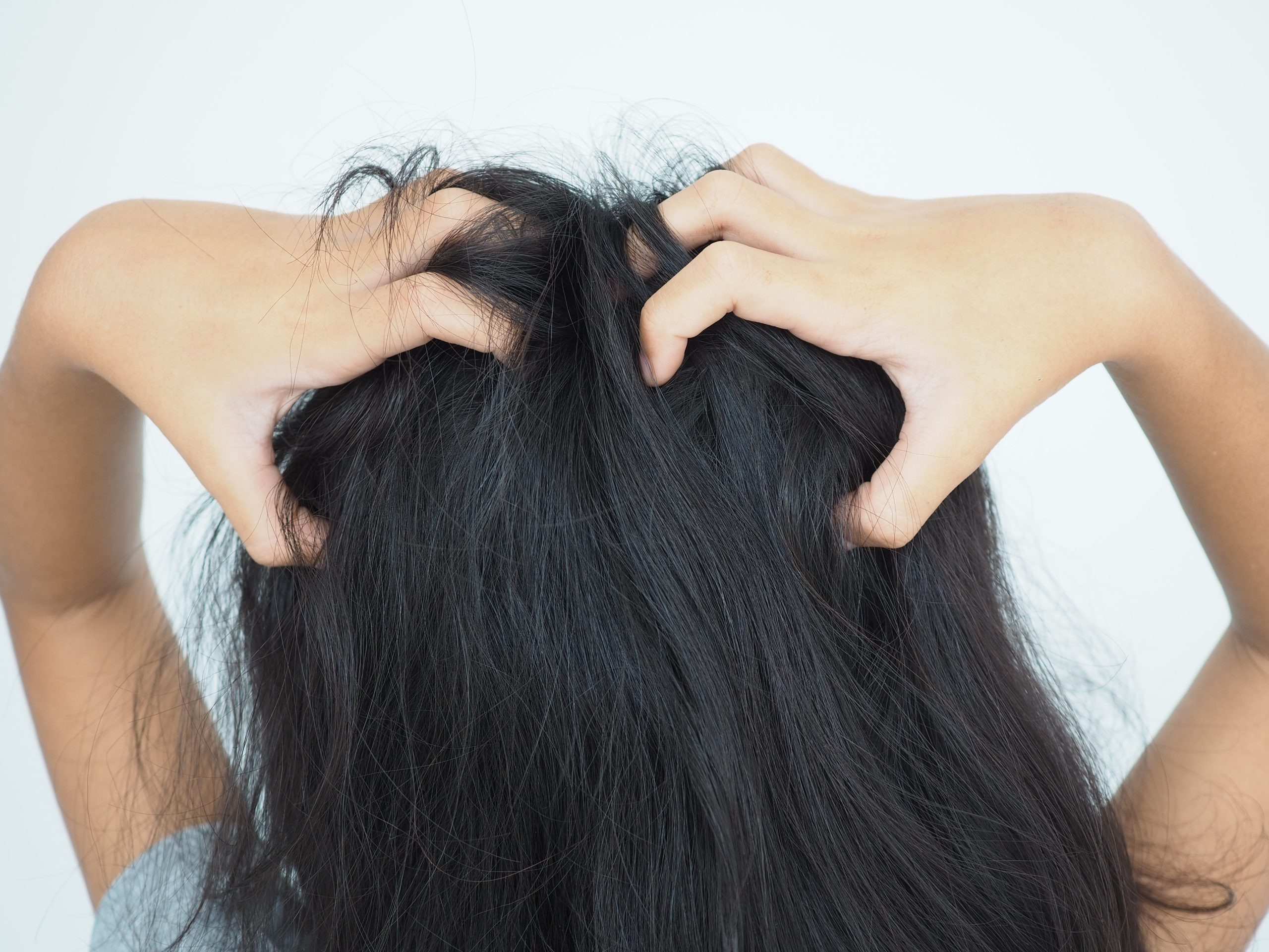 Young girl scratching her itchy scalp, a common nighttime sign of head lice.