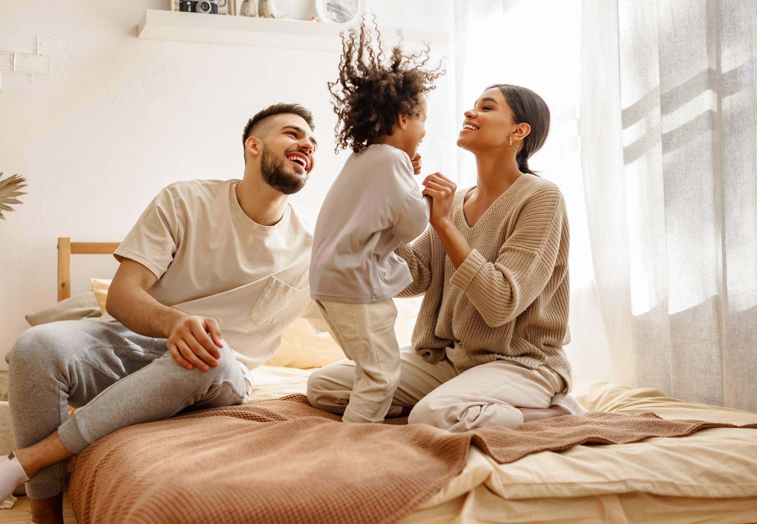 Family jumping on bed for article debunking common head lice myths