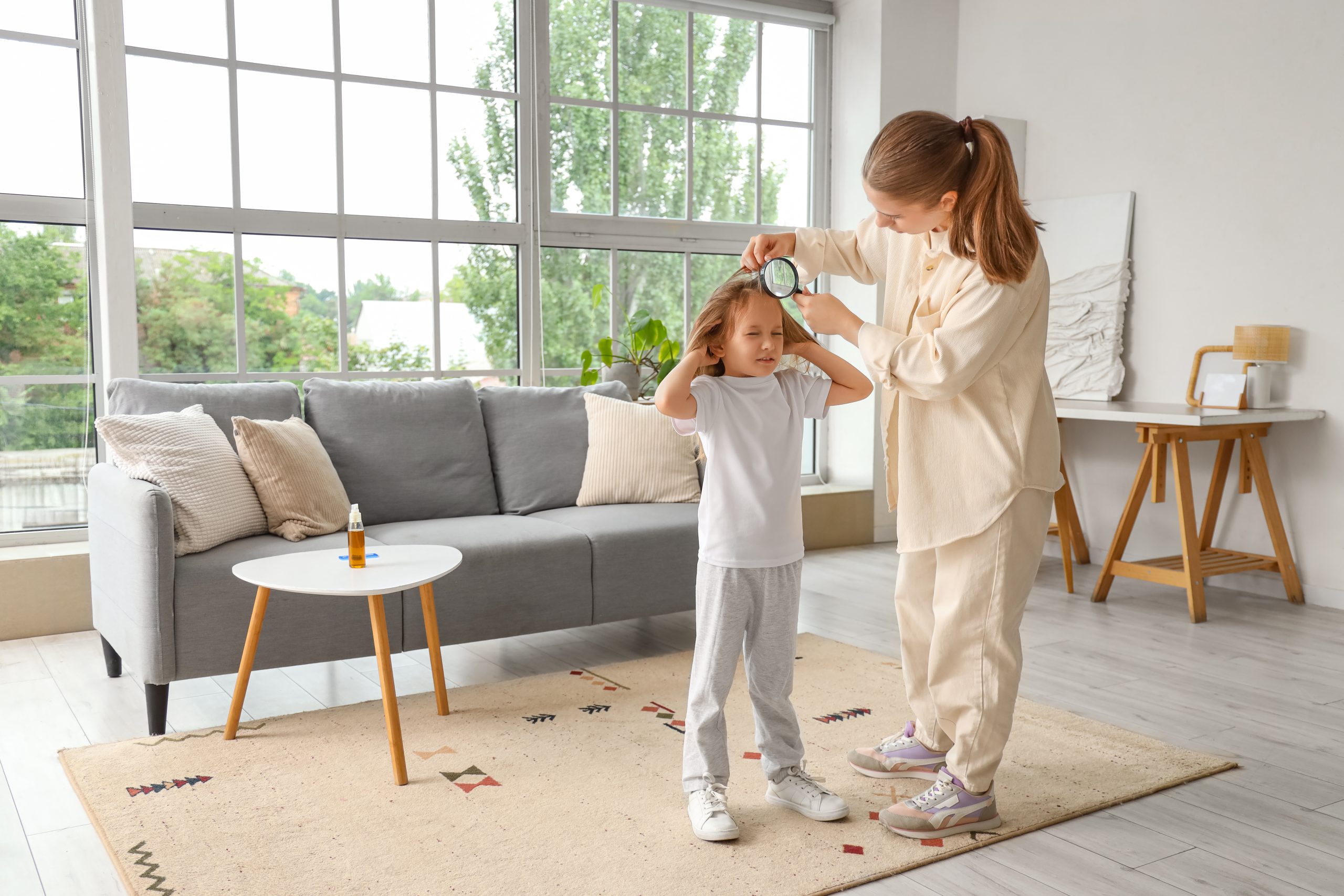 Parent checking child hair with magnifier for article about kids getting lice repeatedly