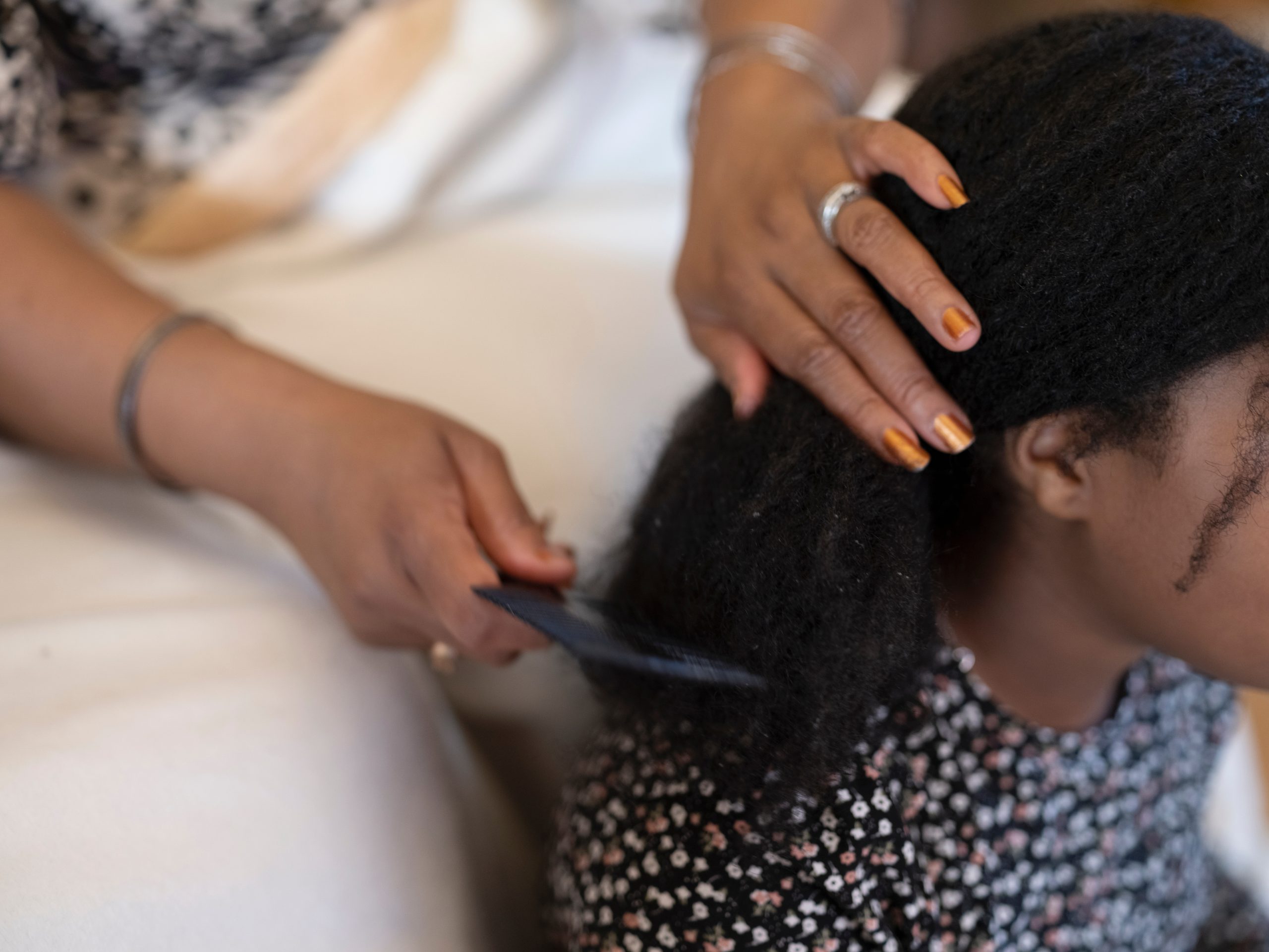 Hands hold and comb a section of dark textured hair.